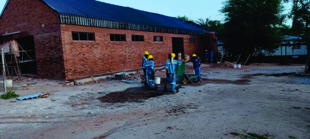 Red-brick warehouse under construction with workers on site, Beitbridge.