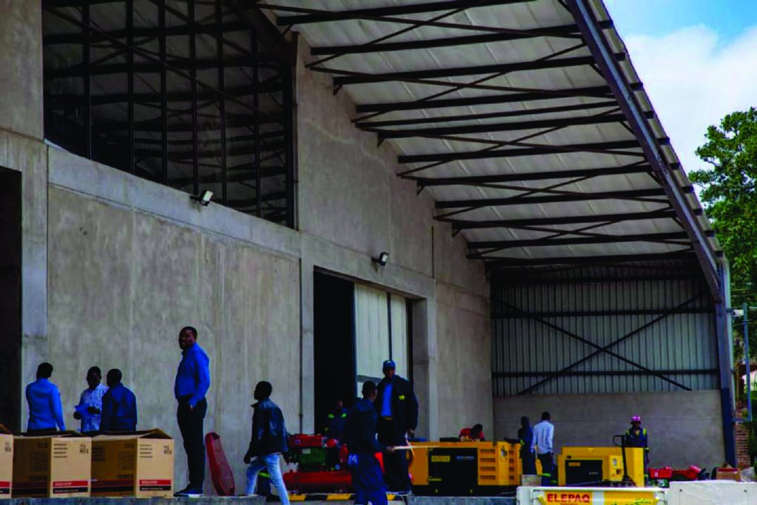 Loading bay of the completed warehouse with steel roof trusses and staff unloading equipment.